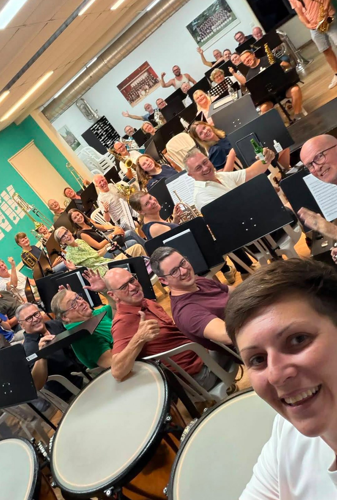Groepsselfie van het orkest in de repetitieruimte, genomen vanuit de paukenhoek